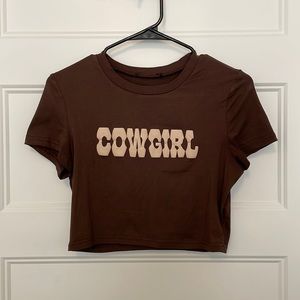 Brown cropped short sleeve t-shirt with “cowgirl” written across.